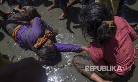 Seorang wanita Muslim Rohingya, yang menyeberang dari Myanmar ke Bangladesh, terbaring tak sadarkan diri di tepi Teluk Bangal setelah kapal yang dia tumpangi terbalik di Shah Porir Dwip, Bangladesh.