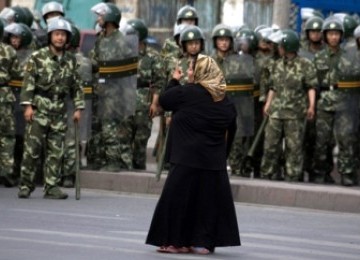 Seorang wanita Muslim Uighur  di Urumqi berhadapan dengan militer Cina