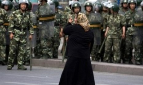 Seorang wanita Muslim Uighur  di Urumqi berhadapan dengan militer Cina