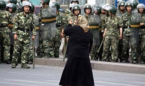 Seorang wanita Muslim Uighur di Urumqi, Xinjiang, berhadapan dengan militer Cina