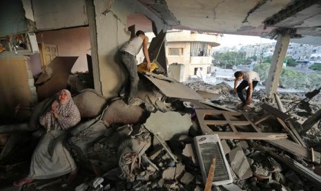  Seorang wanita Palestina duduk di dalam rumahnya yang hancur akibat serangan udara Israel, di Kota Gaza, Kamis (17/7).  (Reuters/Finbarr O'Reilly)