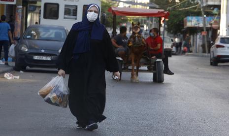 Qatar Janjikan Bantuan 360 Juta Dolar AS untuk Gaza. Seorang wanita Palestina mengenakan masker wajah membawa belanjaannya selama karantina yang diberlakukan menyusul ditemukannya kasus virus corona di Jalur Gaza, Kamis, 27 Agustus 2020. Pada hari Rabu, penguasa Hamas di Gaza memperpanjang penguncian penuh di kantong Palestina selama tiga hari lagi. karena kasus virus korona meningkat setelah deteksi minggu ini dari komunitas penularan virus pertama di wilayah padat penduduk yang diblokir.