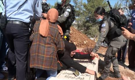 Seorang wanita Palestina terlihat melawan polisi Israel yang mencoba mendorongnya dari batu nisan putranya yang terletak di pemakaman Al-Yusufiye, Yerusalem Timur, Senin (25/10). Alaa Nababta (54 tahun) tiba di kuburan setelah mengetahui rencana polisi Israel untuk menggali kuburan tersebut. Kru kotamadya Israel di Yerusalem dan Otoritas Alam Israel untuk mendirikan taman nasional Yahudi, kembali meruntuhkan bagian dari pemakaman Al-Yusufiya yang terletak dekat Masjid Al Aqsa.