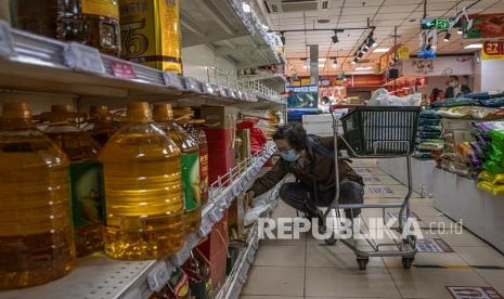 Seorang wanita tua yang mengenakan masker pelindung memilih di samping rak dengan minyak goreng, beras dan tepung di supermarket, di tengah pandemi virus corona, di Beijing, China, Kamis (4/11/2021). Kementerian Perdagangan China mendesak warganya untuk menjaga persediaan kebutuhan sehari-hari dalam keadaan darurat, dengan beberapa pergi ke supermarket untuk membeli persediaan makanan tambahan, terutama minyak untuk memasak dan nasi, serta sayuran, harga yang naik dalam beberapa minggu terakhir setelah hujan lebat yang tidak biasa.