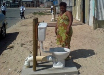 Seorang warga Afrika Selatan mengamati toilet terbuka di lingkungannya