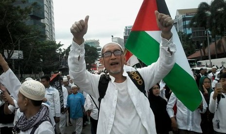 Seorang warga asal Bandung Otje Ardawilaga mengacungkan jempol di tengah acara aksi Bela Palestina di Lapangan Monas, Jakarta, Ahad (17/12).