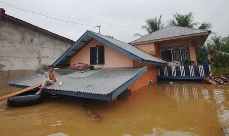 Seorang warga berada di atap rumahnya saat  banjir merendam Nagari Pangkalan, Kabupaten Limapuluhkota, Sumatera Barat, Senin (8/2).   (Antara/Iggoy el Fitra)