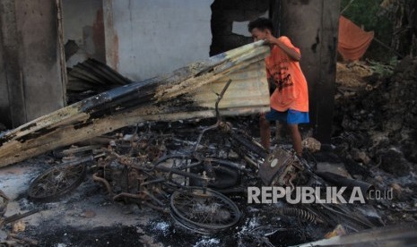 Seorang warga berada di bangkai dua unit sepeda motornya yang terbakar didalam rumahnya pasca keributan antar pemuda di Desa Gunung Jaya, Buton, Sulawesi Tenggara, Kamis (6/6/2019).