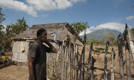 Seorang warga beraktifitas di rumahnya yang berjarak sekitar 10 kilometer dari Gunung Agung yang berstatus awas di Desa Datah, Karangasem, Bali, Selasa (26/9).