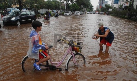  Seorang warga berfoto dengan anaknya di tengah banjir Jalan Boulevard Barat, Kelapa Gading, Jakarta Utara, Jumat (17/1).  (Republika/Rakhmawaty La'lang)