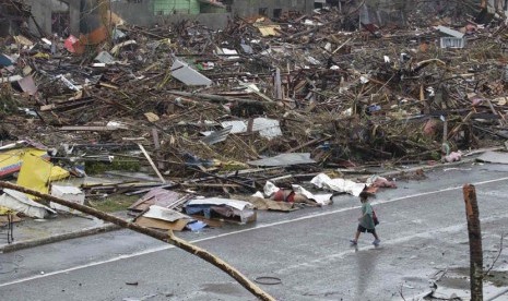  Seorang warga berjalan melewati pemukiman yang hancur akibat Topan Haiyan di kota Tacloban, Leyte provinsi Leyte, Filipina tengah, Ahad (10/11).  (AP/Bullit Marquez)