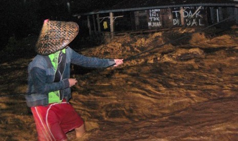  Seorang warga berpegangan pada sebuah tali saat banjir bandang di Padang, Sumbar (ilustrasi)