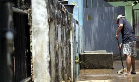 Seorang warga berusaha mengeringkan sisa air akibat banjir yang menenggelamkan rumahnya di Komplek Dosen IKIP, Jati Asih, Bekasi, Jawa Barat