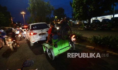 Seorang warga difabel menaikan kursi rodanya keatas motor seusai beraktifitas di Kawasan Basuki Rahmat, Jakarta Timur, Selasa (24/1) malam.