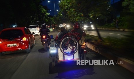 Seorang warga difabel menaikan kursi rodanya keatas motor seusai beraktifitas di Kawasan Basuki Rahmat, Jakarta Timur, Selasa (24/1) malam.