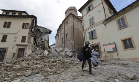 Seorang warga Italia melintas di depan menara lonceng yang runtuh gereja Santa Maria in Via di Kota Camerino, Italia tengah setelah diguncang gempa 5,9 SR, Kamis, 27 Oktober 2016.