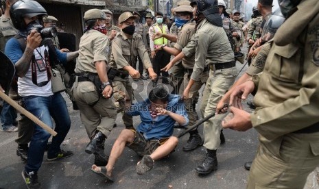 Seorang warga Kampung Pulo terluka dan dibawa petugas saat terjadi bentrok ketika penertiban bangunan Kampung Pulo,, Jatinegara, Jakarta, Kamis (20/8).  (Republika/Wihdan)