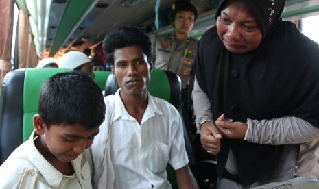 Seorang warga (kanan) menangis melepas pemindahan Husain (kiri) salah seorang anak imigran etnis Rohingya, Myanmar pada proses pemindahan dari penampungan sementara, Pangkalan Susu, Langkat, Sumatera Utara, Senin (18/5).