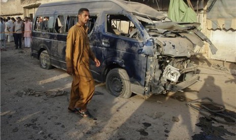 Seorang warga melewati bangkai mobil usai serangan bom mengguncang Peshawar, Pakistan, pada Rabu (19/9). 