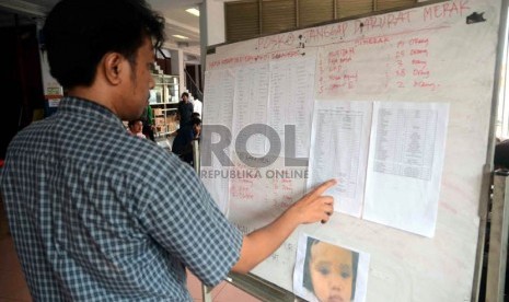   Seorang warga melihat data nama-nama korban dalam kecelakaan kapal Bahuga Jaya di pelabuhan Merak, Banten, Rabu (26/9). (Agung Supriyanto/Republika)