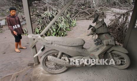 Seorang warga melihat sepeda motor yang tertutup debu vulkanik akibat erupsi gunung Semeru di Pronojiwo, Lumajang, Jawa Timur, Ahad (5/12/2021). Luncuran awan panas akibat letusan gunung Semeru mengakibatkan puluhan rumah di dua kecamatan rusak dan delapan kecamatan terdampak abu vulkanik. 