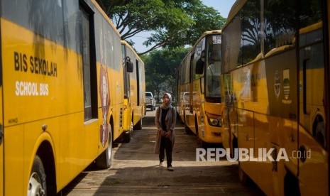 Seorang warga melintas di antara bus sekolah yang terparkir di Balai Pengujian Kendaraan Dinas Perhubungan, Gedebage, Bandung, Jawa Barat. Bus sekolah di Kota Bandung mulai kembali beroperasi pada Senin (18/7/2022).