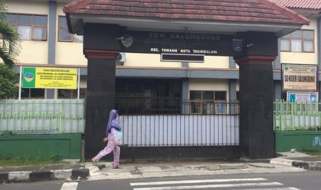 Seorang warga melintas di depan SDN Galunggung, Kelurahan Tawangsari, Kecamatan Tawang, Kota Tasikmalaya, Senin (11/3). 