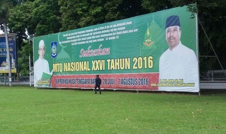 Seorang warga melintas di depan spanduk raksasa MTQ Nasional XXVI  di depan salah satu gedung instansi Pemerintah Provinsi NTB , di Mataram, Kamis (14/7/2016). MTQ Nasional XXVI akan digelar di Mataram, 28 Juli hingga 6 Agustus 2016.