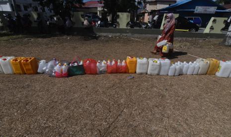 Seorang warga melintas di deretan jerigen yang diletakkan warga saat antre untuk mendapatkan minyak goreng curah yang didistribusikan pada gelaran pasar murah di Palu, Sulawesi Tengah, Kamis (21/4/2022). Distribusi minyak goreng curah pada gelaran pasar murah yang diselenggarakan oleh Pemerintah Kota Palu tersebut diserbu warga yang datang dan antre sejak dini hari untuk membeli minyak goreng curah seharga Rp14 ribu per liter dengan jumlah pembelian maksimal 10 liter per orang.