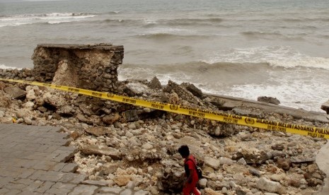 Seorang warga melintas di dermaga tempat wisata kuliner yang rusak akibat diterjang gelombang tinggi di pesisir pantai Kota Kupang, NTT, Jumat (25/1/2019). Gelombang tinggi yang terjadi Rabu sejak Rabu (23/1) sampai saat ini telah menghancurkan sejumlah lokasi wisata di kota itu seperti dermaga tempat wisata kuliner serta sejumlah kafe berwarna.