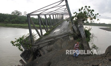 Seorang warga melintas di samping konstruksi jembatan rangka baja penghubung Kecamatan Kaway XVI dan Kecamatan Pante Ceureumen yang rusak di Desa Sawang Teube, Kaway XVI, Aceh Barat, Aceh, Senin (12/11/2018). 