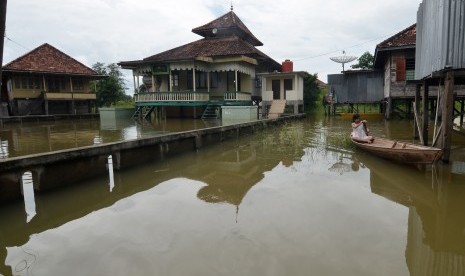 Seorang warga melintas menggunakan perahu di halaman rumahnya yang digenangi air luapan Sungai Batanghari, ilustrasi