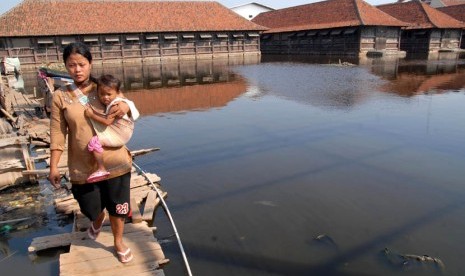  Seorang warga melintasi genangan air banjir rob. (Agung Fatma Putra/Republika)