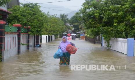 Seorang warga melintasi genangan air menuju lokasi pengungsian di Desa Garut, Kecamatan Darul Imarah, Kabupaten Aceh Besar, Aceh, Jumat (8/5/2020). Curah hujan tinggi yang terjadi sejak Minggu (7/5/2020) mengakibatkan air sungai Krueng Daroy meluap dan merendam ratusan rumah dengan ketinggian air 50-130 centimeter sehingga membuat sebagian warga mengungsi.