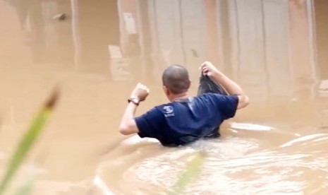 Seorang warga melintasi jalan yang sudah tertutup oleh banjir di Jakarta