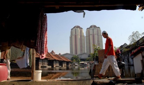  Seorang warga melintasi pemukiman yang terkena banjir air rob  di kawasan Penjaringan,Jakarta Utara,Ahad (22/7). (Agung Fatma Putra/Republika)