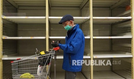 Seorang warga melintasi rak penjualan beras yang kosong di sebuah supermarket di Hong Kong, Kamis, (6/2). Warga memborong berbagai kebutuhan dasar di toko-toko seiring merebaknya wabah virus corona dari China daratan.