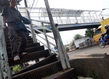 Seorang warga melintasi salah satu anak tangga yang rusak di jembatan penyebrangan orang (JPO) di Jakarta, Sabtu (31/3). (Republika/Agung Fatma Putra)