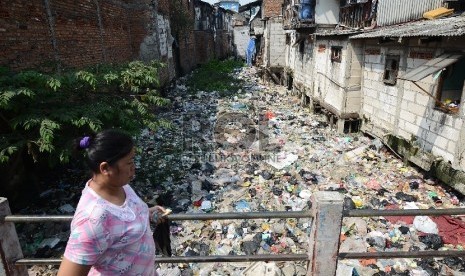 Seorang warga melintasi sungai yang dipenuhi sampah di Muara Baru, Jakarta utara, Selasa (19/5).