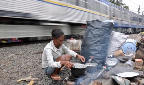 Seorang warga memanfaatkan area bantaran rel kereta api untuk memasak di kawasan Karet, Jakarta Barat, Kamis (7/2).   (Republika/Rakhmawaty La'lang)