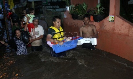   Seorang warga membawa anaknya yang masih balita ketika melintasi banjir yang merendam kawasan Kampung Pulo, Jakarta, Ahad (12/1).    (Republika/Yasin Habibi)