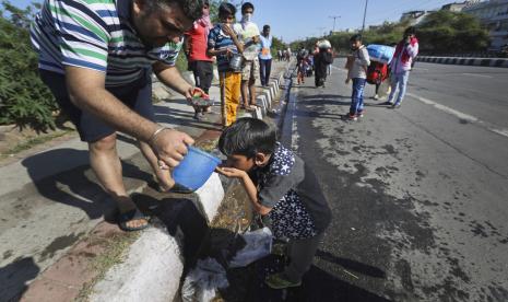 Seorang warga memberi minum pada anak migran di New Delhi, India, Jumat (27/3). Bank Dunia menyebutkan negara di Asia-Pasifik harus segera melakukan mitigasi atas dampak ekonomi yang disebabkan oleh Covid-19.