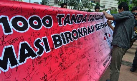  Seorang warga memberikan tanda tangannya disebuah spanduk saat aksi gerakan 1000 tanda tangan peduli reformasi birokrasi kesahatan di kawasan Bundaran HI, Jakarta, Ahad (3/2).   (Republika/Agung Supriyanto)