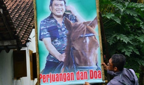 Seorang warga memegang baliho bergambar penyanyi dangdut Rhoma Irama di pinggir jalan Desa Pangkah, Tegal, Jateng, Jumat (21/3). 