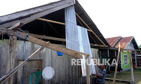 Seorang warga memperbaiki atap rumahnya yang rusak akibat angin kencang di Desa Papalang, Kecamatan Papalang, Mamuju, Sulawesi Barat.