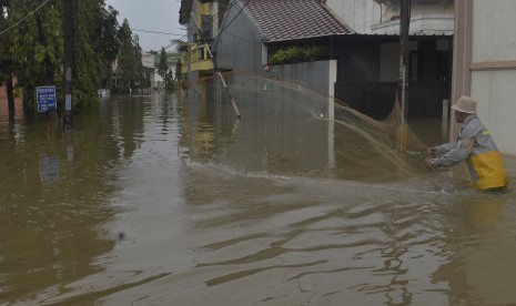 Seorang warga mencari ikan dengan jalan ketika terjadi banjir di Kompleks IKIP Jati Bening, Bekasi, Senin (20/2). 