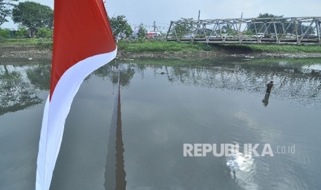 Seorang warga mencari ikan di bantaran Sungai Citarum dengan latar bendera merah putih di atas Sungai Citarum, kecataman Baleendah, Kabupaten Bandung, Jumat (12/8). 