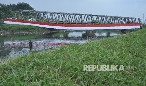 Seorang warga mencari ikan di bantaran Sungai Citarum dengan latar bendera merah putih di atas Sungai Citarum, kecataman Baleendah, Kabupaten Bandung, Jumat (12/8).