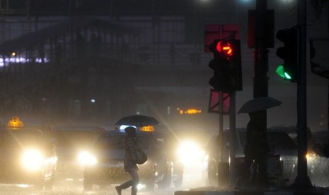 Seorang warga menembus hujan menggunakan payung di Jalan Gajah Mada, Jakarta, Senin (30/11).