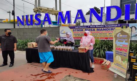 Seorang warga menerima paket takjil di Posko Nusa Mandiri Tower Jatiwaringin, Jakarta.